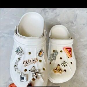 White crocs with croc charms as well as a mystery pack of charms